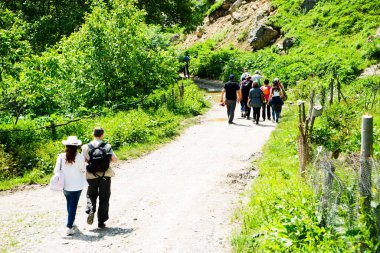 Sırt çantalı bir grup insan yol boyunca yürüyor. Ufukta dağlar var. Gökyüzü mavi ve bulutlu. seyahat turizmi kavramı.