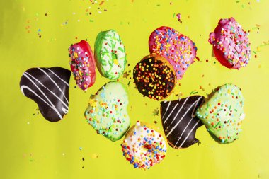 Sarı arka planda çok renkli çörekler izole edilmiş. Üst görünüm