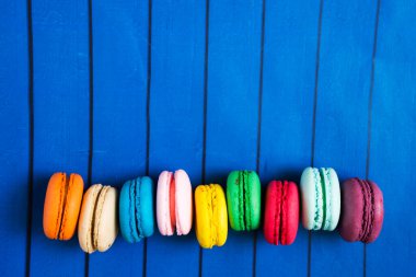 Mavi ahşap arka planda tatlı ve renkli Fransız kurabiyeleri.