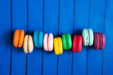 Mavi ahşap arka planda tatlı ve renkli Fransız kurabiyeleri.