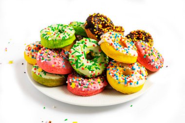 Beyaz arka planda beyaz bir tabakta renkli çörekler..