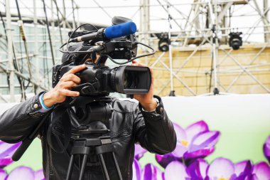 Şehir parkında video kamerasıyla çekim yapan bir kameraman.