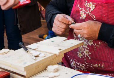 Fez, Fas - 07 Ocak 2020: Bilinmeyen bir adam ahşap işinde çalışıyor veya sokak pazarının yakınında oyma atölyesi işletiyor. Etrafında bir sürü ahşap hediyelik eşya ve ürün vardı.