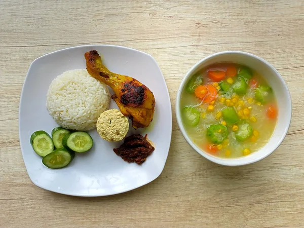 Healthy food. A plate of white rice with grilled chicken and a bowl of soup on the table, top view