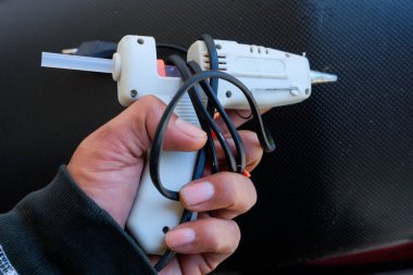 Elektrikli yapıştırıcı tabancasını tutan ve sanat veya el işi için kullanan bir elin yakın çekimi.