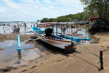 A fishing boat that ran aground on the beach due to low tide against a blue sky