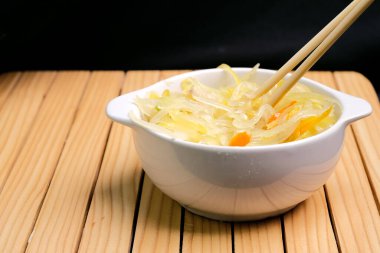 Saute grated young papaya in a white bowl on a wooden table. Traditional dishes from Indonesia