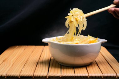 Sauteed young papaya with hot chili peppers in a white bowl on a wooden table. Traditional dishes from Indonesia