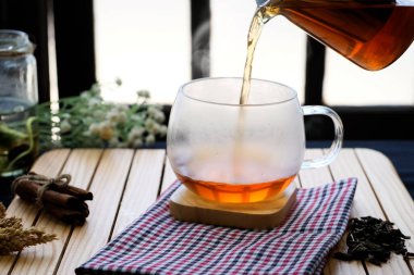 Herbal hot tea drink in glass with steam on old background in composition on table