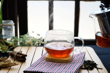 Herbal hot tea drink in glass with steam on old background in composition on table