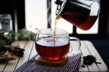 Herbal hot tea drink in glass with steam on rustic background in composition on table