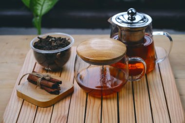 Hot herbal tea drink in glass composition with cinnamon on a wooden pallet