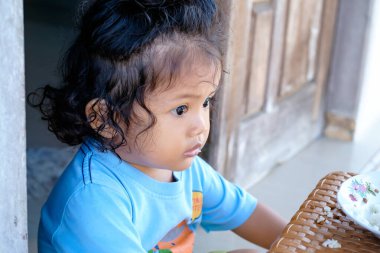 Kıvırcık saçlı, çok kültürlü çocuk pirinç kahvaltısı yapıyor. Asyalı çocuk kendine güveniyor