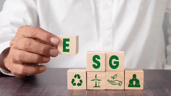 ESG concept of governance and social environment. Sustainable company development. Hand holding wooden cube with letter E icon