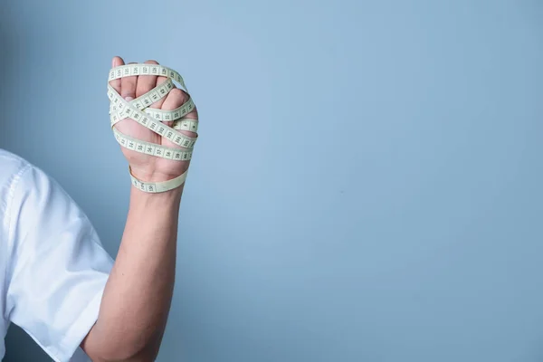 Mann Bandagiert Seine Hand Mit Maßband Auf Hellblauem Hintergrund Gewichtsverlust — Stockfoto