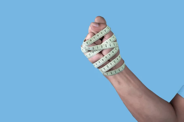 Man Bandaging Sin Hand Med Måttband Ljusblå Bakgrund Viktminskning Koncept — Stockfoto