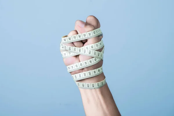 Man Bandaging Sin Hand Med Måttband Ljusblå Bakgrund Viktminskning Koncept — Stockfoto