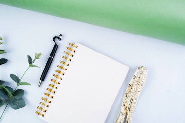 Beyaz arka plan, diyet ve sağlıklı yaşam konsepti üzerine kalem ve mezura içeren defter