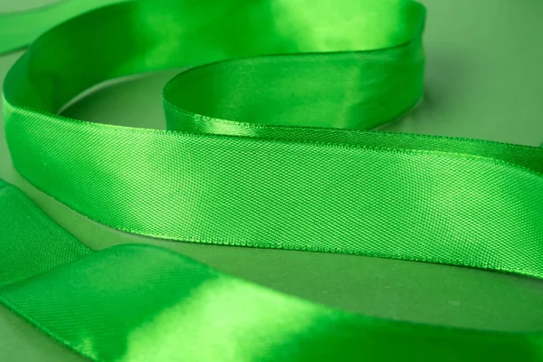 Closeup of green ribbon, April Green month of awareness about the importance of safety at work.
