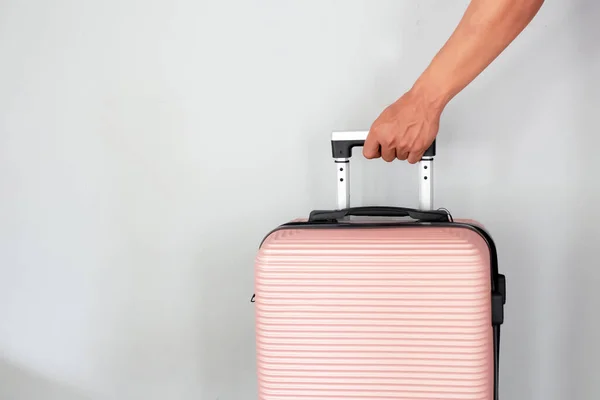 Männliche Hand Hält Einen Pfirsichfarbenen Koffer Auf Grauem Hintergrund Urlaubskonzept — Stockfoto