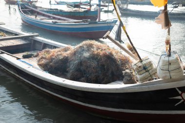 İskeledeki bir teknede balık ağı ve yosun yığını.