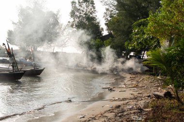 Suyun üzerinde sisli bir sabahla sahilde balıkçı teknesi