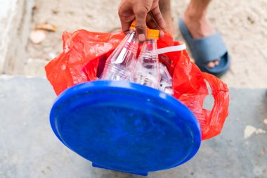 Erkek eli boş plastik su şişesini geri dönüşüm kutusuna atıyor.