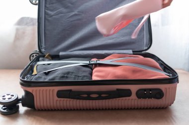 Seyahat için hazırlanmış elbiselerle birlikte pembe bavulu aç. Seyahat kavramı