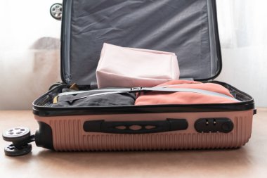 Seyahat için hazırlanmış elbiselerle birlikte pembe bavulu aç. Seyahat kavramı