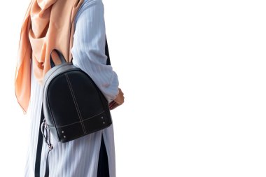Beyaz arka planda askı çantasıyla duran Müslüman kadının yan görüntüsü. Seyahat kavramı