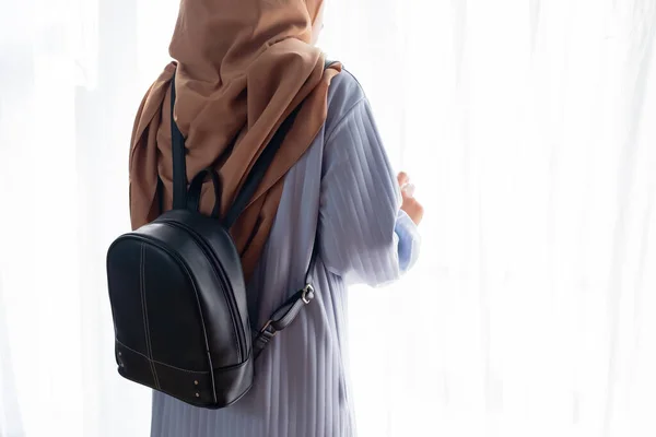 Side view of Muslim woman standing with sling bag on white background. Travel concept