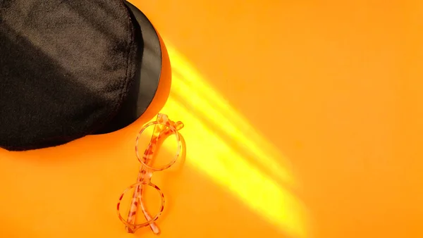 Vista Superior Sombrero Negro Gafas Sobre Fondo Naranja Luz Del —  Fotos de Stock