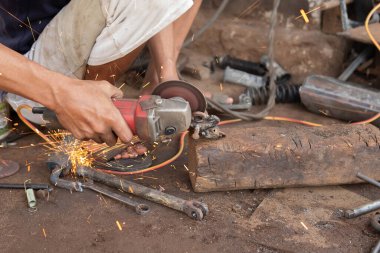 Öğütücüyle metal kesen bir kaynakçı kaynak yapmaya hazırlanıyor.