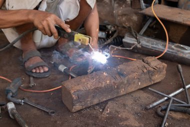 Kaynakçılar kaynak metali üzerinde çalışırlar. Kaynak atölyesinde çalışan adamlar.