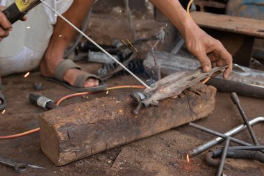 Kaynakçılar kaynak metali üzerinde çalışırlar. Kaynak atölyesinde çalışan adamlar.