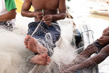 Balıkçı Endonezya 'daki köyde balıkçı ağlarını tamir ediyor.