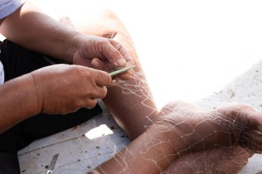 Adam Endonezya 'da bir köyde bir balıkçı teknesini tamir ediyor.