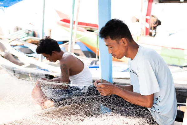 stock image Lampung, Indonesia, June 18 2023: The fisherman is repairing the fishing net on the boat in the village, Indonesia