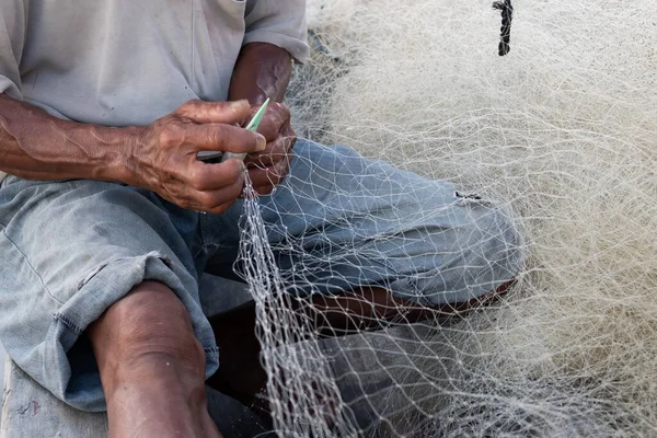 男はインドネシアの村で漁船の網を修理している ロイヤリティフリーのストック画像