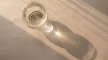 Masada güneş ışınlarının yansıması olan cam bardak. minimalist kavram