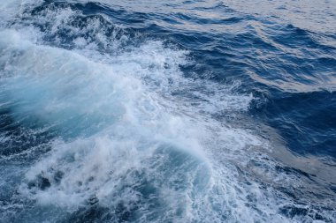 Dalgalar ve sıçramalarla mavi deniz suyunun en üst görüntüsü