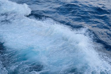 Dalgalar ve sıçramalarla mavi deniz suyunun en üst görüntüsü