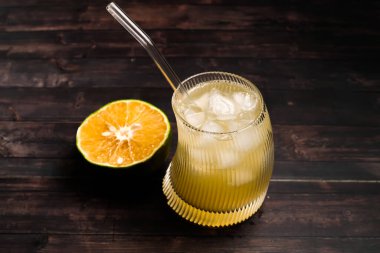 Tahta arka planda bir bardakta taze portakal suyu.