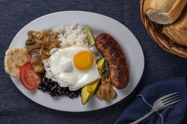 Bandeja paisa 'nın üst görüntüsü, Kolombiya' nın tipik mavi masa örtüsü üzerindeki yiyeceği..