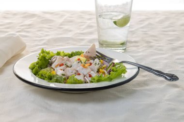 Ceviche, beyaz masa örtüsü üzerinde Peru mutfağının tipik balık tabanlı yemeği..
