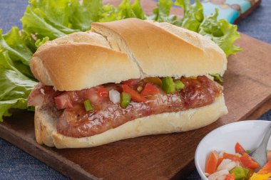 Choripan, typical argentine sandwich with chorizo and creole sauce on a wooden board. clipart