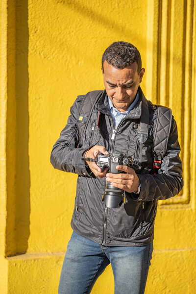 Латиноамериканский фотограф проверяет фотографию на своей камере.
