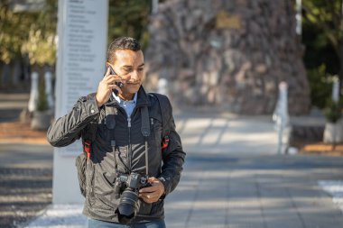 Sokakta çalışan ve cep telefonuyla konuşan bir fotoğrafçı..