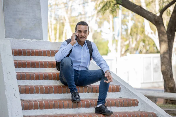 Mladý Latinoameričan Sedí Schodech Památníku Mluví Svém Mobilním Telefonu — Stock fotografie