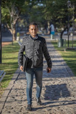 Latin genç adam parkta yürüyor..